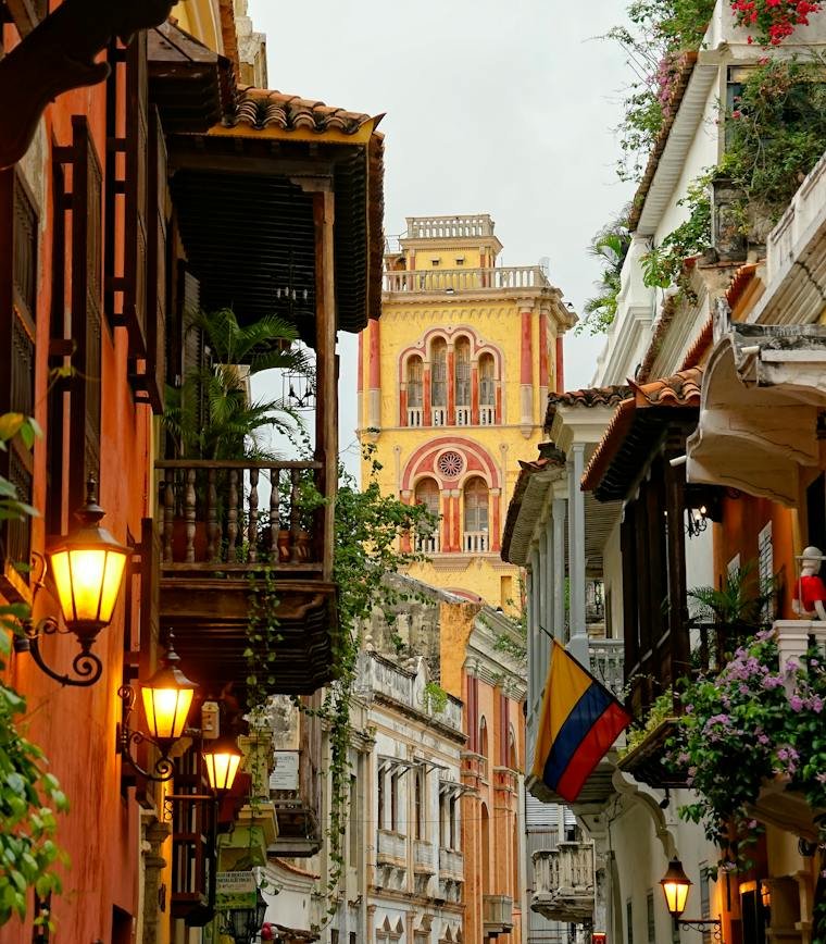 Calle colonial de Cartagena con fachadas coloridas y una iglesia al fondo